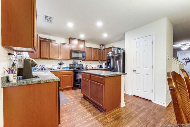 8514 Bayliss Pt, San Antonio, TX 78252 - kitchen with black appliances, light wood finished floors, a kitchen island, recessed lighting, and baseboards