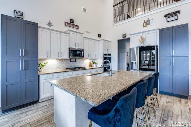 28806 Oldlyme, San Antonio, TX 78260 - kitchen featuring stainless steel appliances, a sink, a high ceiling, light wood finished floors, and a kitchen bar