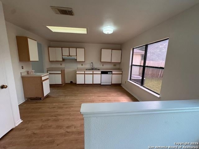 7011 Cole Crk, Converse, TX 78109 - kitchen featuring white dishwasher, a sink, wood finished floors, white cabinets, and under cabinet range hood
