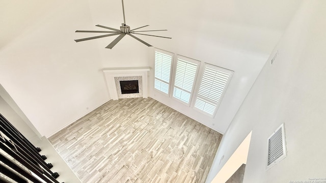 10828 Bango Farms, San Antonio, TX 78254 - unfurnished living room featuring a towering ceiling, ceiling fan, light wood-type flooring, and a fireplace