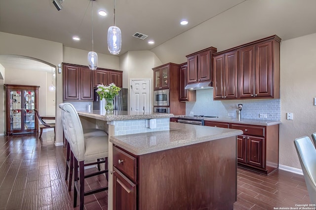 1009 Oak Rdg, Schertz, TX 78154 - kitchen with appliances with stainless steel finishes, arched walkways, a kitchen island, decorative backsplash, and a breakfast bar