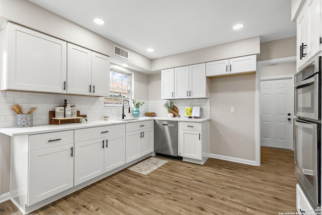 371 Pike, San Antonio, TX 78209 - kitchen with appliances with stainless steel finishes, a sink, white cabinetry, light countertops, and light wood-style floors