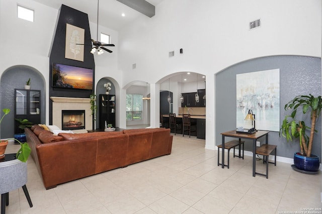 22450 Viajes, San Antonio, TX 78261 - living room with a ceiling fan, arched walkways, a lit fireplace, light tile patterned floors, and a high ceiling