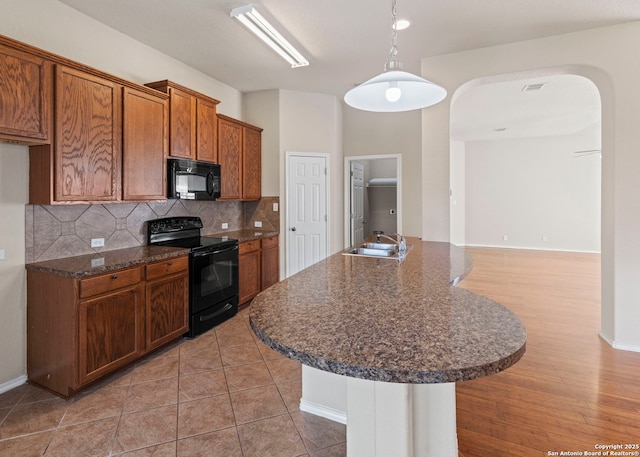 7319 Tranquillo Way, San Antonio, TX 78266 - kitchen featuring black appliances, a sink, arched walkways, tasteful backsplash, and brown cabinets