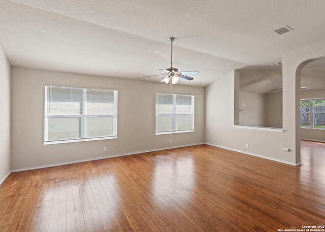 7319 Tranquillo Way, San Antonio, TX 78266 - unfurnished room with wood finished floors, ceiling fan, arched walkways, baseboards, and a textured ceiling