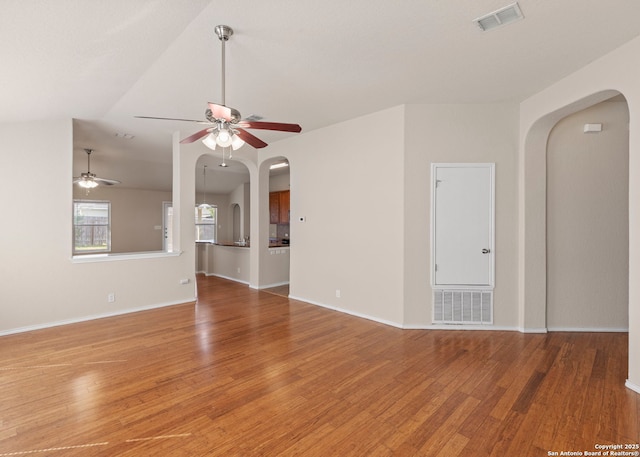 7319 Tranquillo Way, San Antonio, TX 78266 - unfurnished living room with arched walkways, ceiling fan, light wood finished floors, baseboards, and lofted ceiling