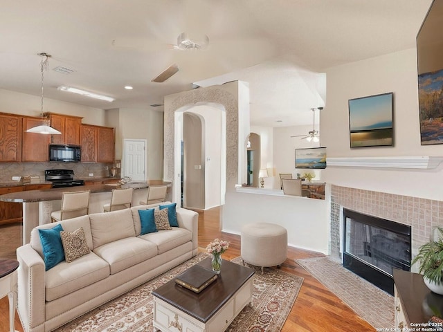7319 Tranquillo Way, San Antonio, TX 78266 - living room featuring ceiling fan, arched walkways, light wood finished floors, and a tile fireplace
