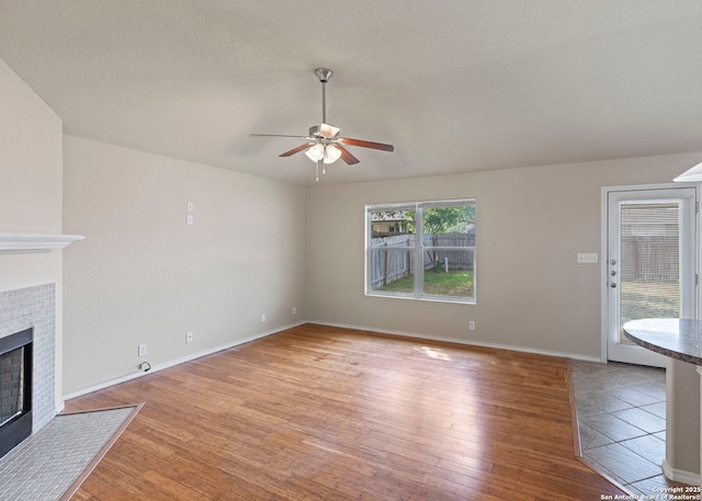 7319 Tranquillo Way, San Antonio, TX 78266 - unfurnished living room featuring a ceiling fan, light wood-type flooring, a fireplace, and baseboards