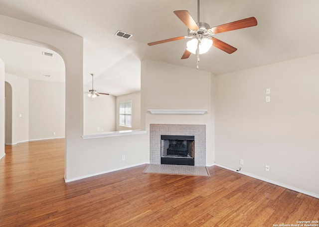 7319 Tranquillo Way, San Antonio, TX 78266 - unfurnished living room with arched walkways, ceiling fan, wood finished floors, a tile fireplace, and vaulted ceiling