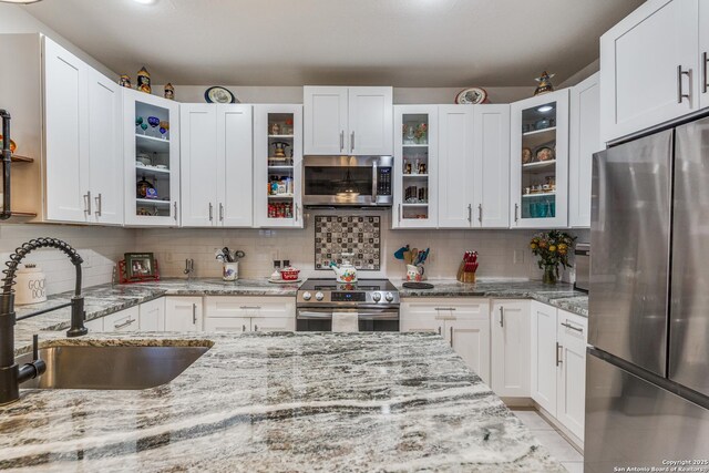 2045 W Mistletoe Ave, San Antonio, TX 78201 - kitchen with stainless steel appliances, a sink, white cabinets, decorative backsplash, and light stone countertops