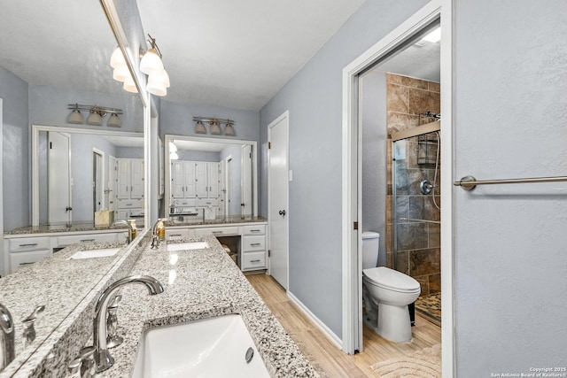 2002 Encino Vly, San Antonio, TX 78259 - full bathroom featuring wood finished floors, double vanity, toilet, a shower stall, and baseboards
