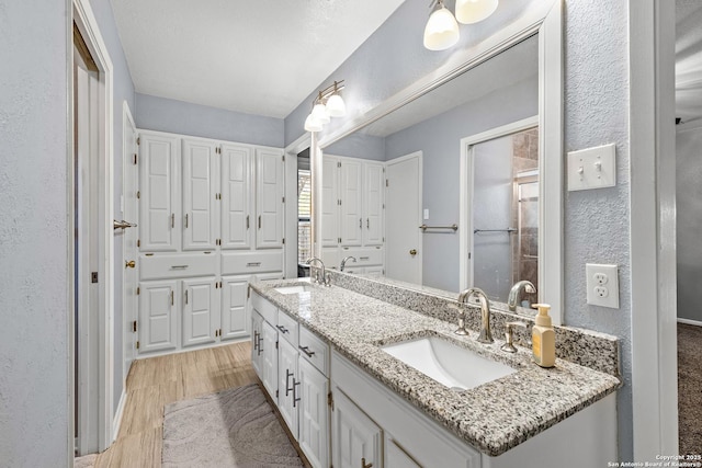 2002 Encino Vly, San Antonio, TX 78259 - bathroom with double vanity, wood finished floors, and a textured wall
