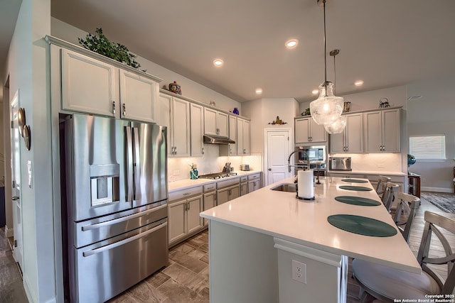 14815 Highdere, San Antonio, TX 78245 - kitchen featuring stainless steel appliances, a sink, a breakfast bar, under cabinet range hood, and backsplash