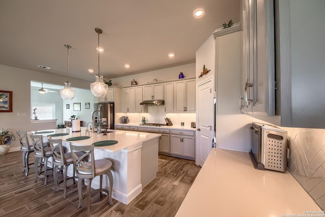 14815 Highdere, San Antonio, TX 78245 - kitchen with wood finish floors, under cabinet range hood, stainless steel appliances, light countertops, and a center island with sink
