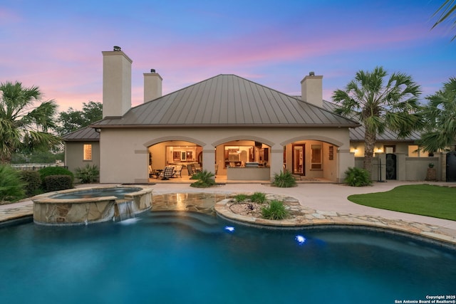 208 Cascade Caverns, Boerne, TX 78015 - back of property at dusk featuring a standing seam roof, metal roof, a chimney, and stucco siding