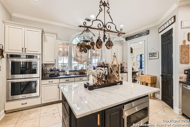 41 Champions Run, San Antonio, TX 78258 - kitchen featuring appliances with stainless steel finishes, tasteful backsplash, crown molding, light tile patterned flooring, and a kitchen island