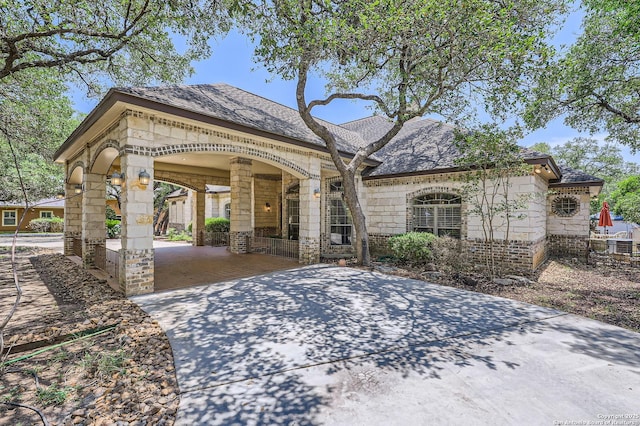 5718 Elam Way, San Antonio, TX 78261 - view of front facade with concrete driveway, stone siding, a carport, brick siding, and roof with shingles