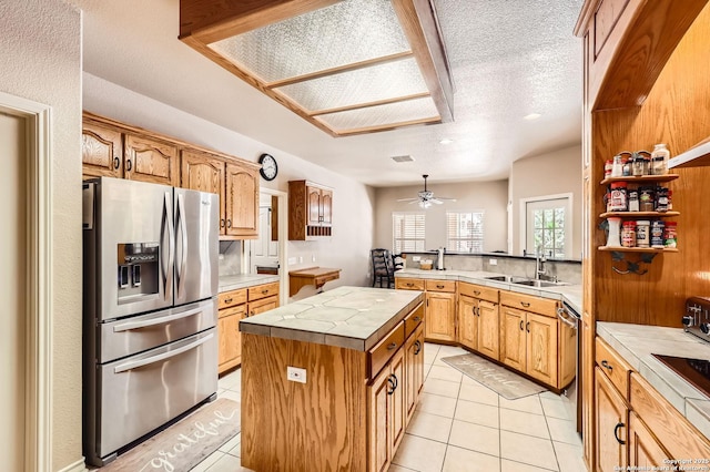 5718 Elam Way, San Antonio, TX 78261 - kitchen featuring appliances with stainless steel finishes, a sink, light tile patterned floors, a kitchen island, and a peninsula