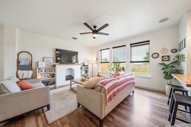 10228 Ancient Anchor, San Antonio, TX 78245 - living room featuring a fireplace, wood finished floors, a ceiling fan, and baseboards