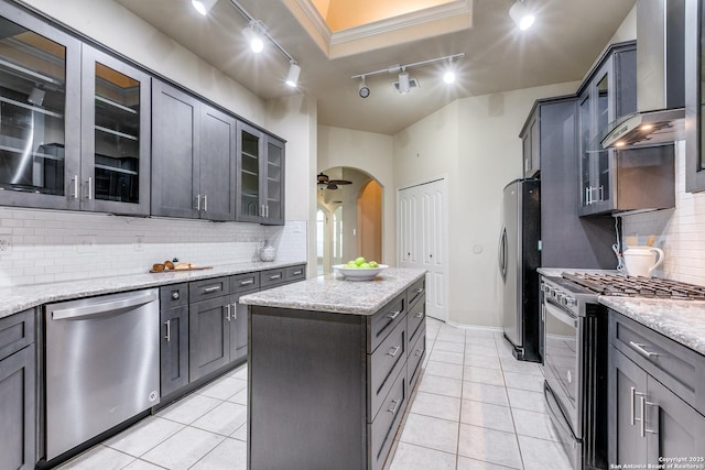 2710 Trinity Rdg, San Antonio, TX 78261 - kitchen featuring rail lighting, stainless steel appliances, wall chimney range hood, decorative backsplash, and a kitchen island