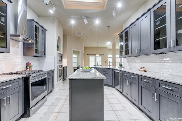 2710 Trinity Rdg, San Antonio, TX 78261 - kitchen featuring appliances with stainless steel finishes, rail lighting, wall chimney range hood, a peninsula, and light stone counters