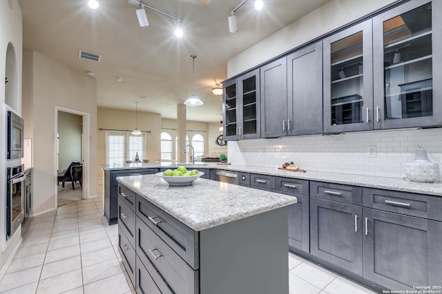 2710 Trinity Rdg, San Antonio, TX 78261 - kitchen with a peninsula, light tile patterned floors, stainless steel appliances, a kitchen island, and tasteful backsplash