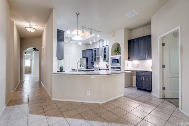 2710 Trinity Rdg, San Antonio, TX 78261 - kitchen featuring stainless steel appliances, arched walkways, light tile patterned flooring, a peninsula, and decorative backsplash