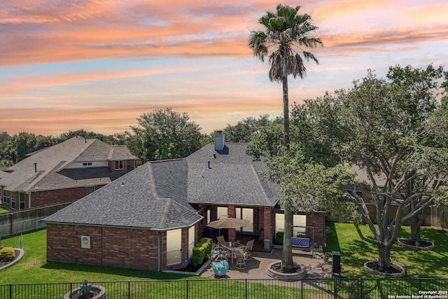 8611 Torry Vw, Houston, TX 77095 - back of house at dusk with brick siding, a patio area, a shingled roof, and a chimney