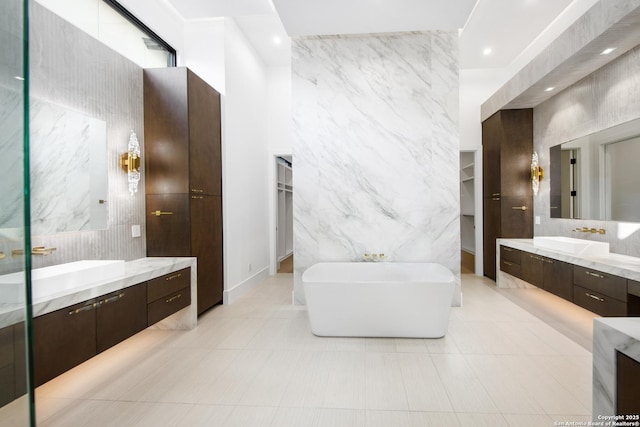 24607 Cliff Line, San Antonio, TX 78257 - bathroom featuring tile walls, a freestanding bath, two vanities, recessed lighting, and a walk in closet