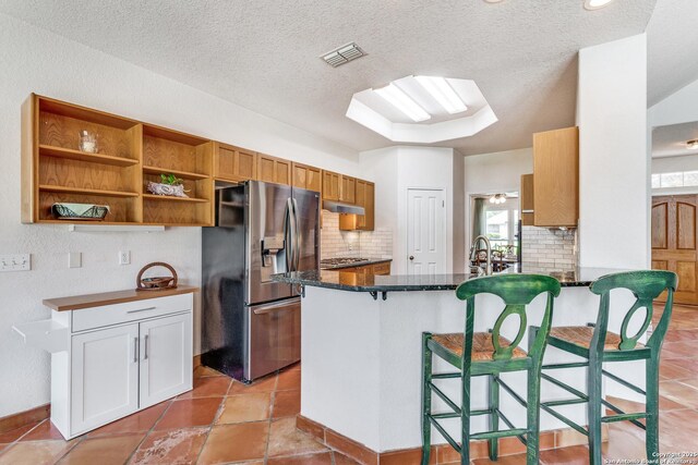 121 Maderas, Seguin, TX 78155 - kitchen with appliances with stainless steel finishes, decorative backsplash, under cabinet range hood, a peninsula, and a textured ceiling
