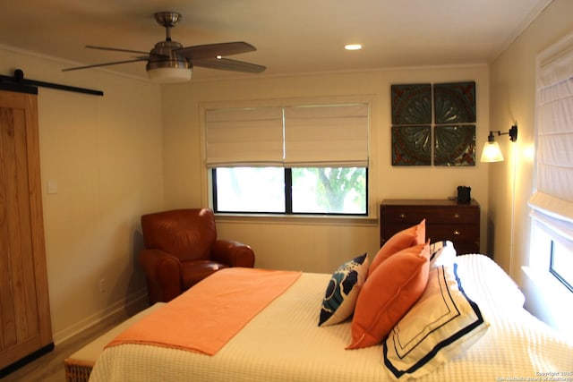 38 Peggy, Palacios, TX 77465 - bedroom with a barn door, wood finished floors, ceiling fan, baseboards, and recessed lighting