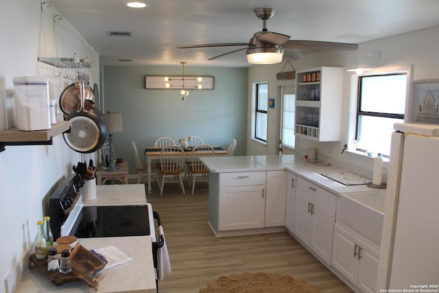 38 Peggy, Palacios, TX 77465 - kitchen with ceiling fan, a peninsula, freestanding refrigerator, white cabinetry, and light countertops