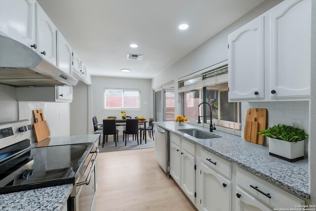 6518 Spring Hurst Dr, San Antonio, TX 78249 - kitchen featuring appliances with stainless steel finishes, a sink, under cabinet range hood, decorative backsplash, and white cabinetry
