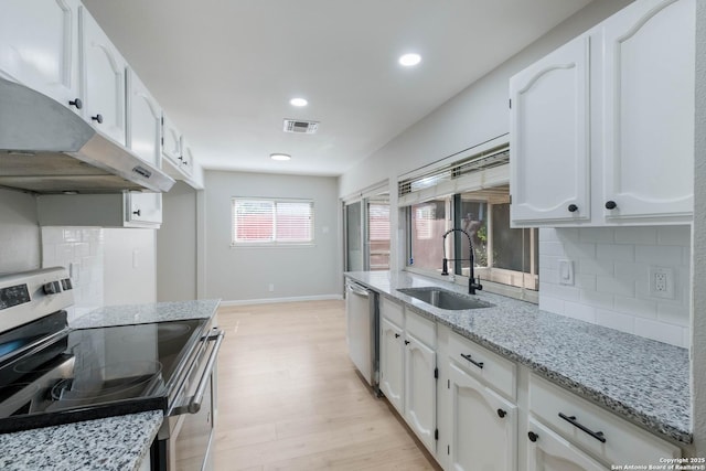 6518 Spring Hurst Dr, San Antonio, TX 78249 - kitchen featuring appliances with stainless steel finishes, under cabinet range hood, a sink, light wood-type flooring, and tasteful backsplash