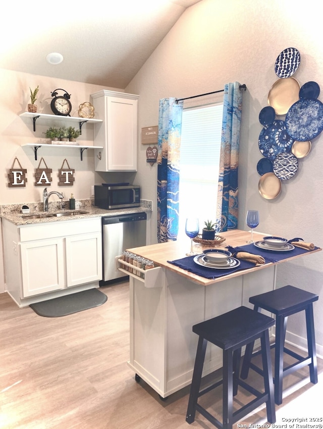 7003 Emerald Vly, San Antonio, TX 78242 - kitchen with appliances with stainless steel finishes, vaulted ceiling, white cabinetry, light wood-type flooring, and a sink