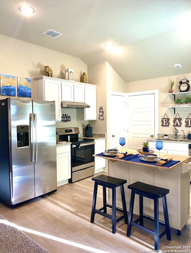 7003 Emerald Vly, San Antonio, TX 78242 - kitchen with stainless steel appliances, white cabinets, under cabinet range hood, lofted ceiling, and light wood-style flooring