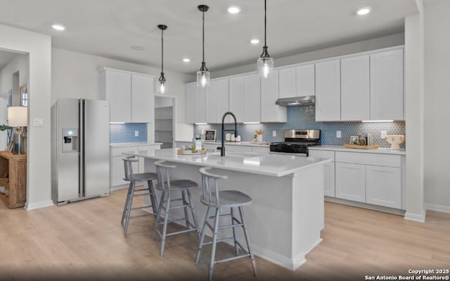 6407 Penny Path, San Antonio, TX 78253 - kitchen featuring appliances with stainless steel finishes, light wood finished floors, under cabinet range hood, tasteful backsplash, and a breakfast bar