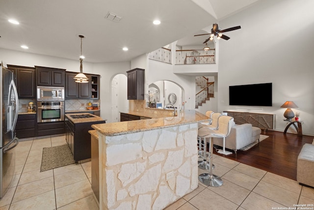 846 Fawnway, San Antonio, TX 78260 - kitchen featuring stainless steel appliances, arched walkways, a breakfast bar area, tasteful backsplash, and light tile patterned floors