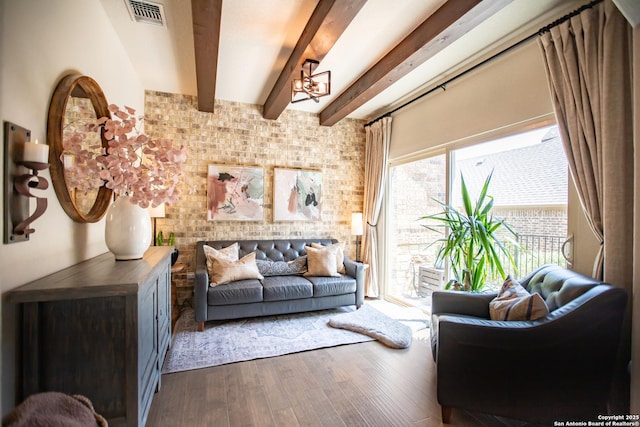 12805 Big Tank Rnch, San Antonio, TX 78245 - living room featuring wood finished floors, beamed ceiling, a chandelier, and brick wall