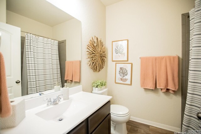 12805 Big Tank Rnch, San Antonio, TX 78245 - full bath with vanity, toilet, wood finished floors, baseboards, and a shower with curtain
