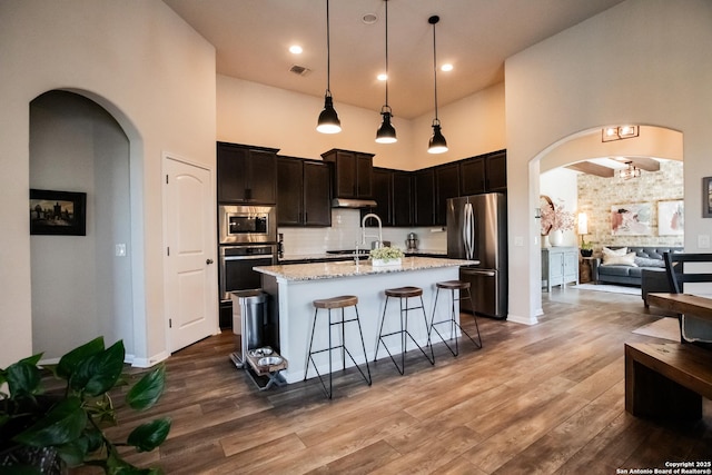 12805 Big Tank Rnch, San Antonio, TX 78245 - kitchen with appliances with stainless steel finishes, a towering ceiling, arched walkways, a kitchen breakfast bar, and wood finished floors