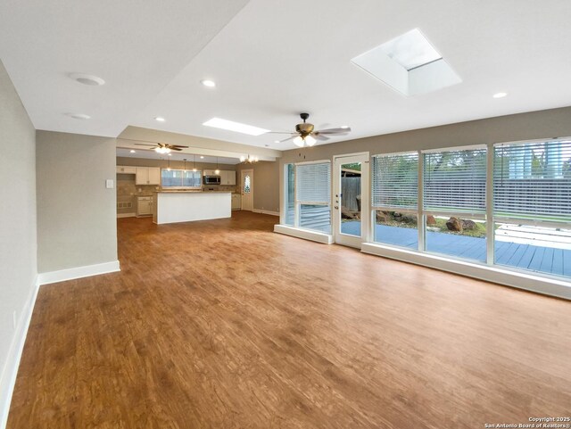 1002 Chevy Chase, San Antonio, TX 78209 - unfurnished living room featuring a skylight, ceiling fan, baseboards, wood finished floors, and recessed lighting
