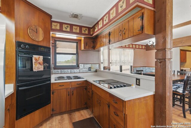 701 Steele, Smiley, TX 78159 - kitchen with black appliances, brown cabinetry, light countertops, and light wood finished floors