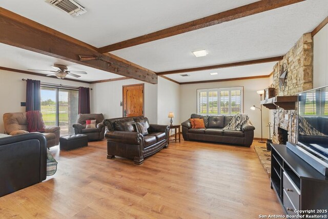701 Steele, Smiley, TX 78159 - living area with healthy amount of natural light, beamed ceiling, light wood finished floors, a stone fireplace, and crown molding