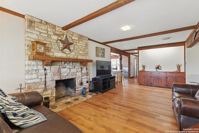 701 Steele, Smiley, TX 78159 - living area featuring beamed ceiling, light wood finished floors, a fireplace, a baseboard radiator, and wooden walls