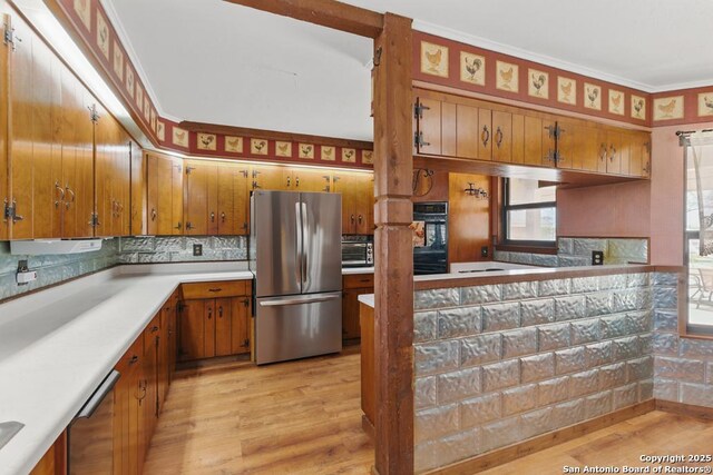 701 Steele, Smiley, TX 78159 - kitchen with stainless steel appliances, brown cabinets, light wood-style floors, tasteful backsplash, and crown molding
