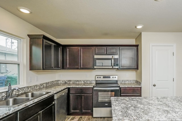 2434 Bermuda, San Antonio, TX 78222 - kitchen with stainless steel appliances, a sink, light wood-style floors, and dark brown cabinets