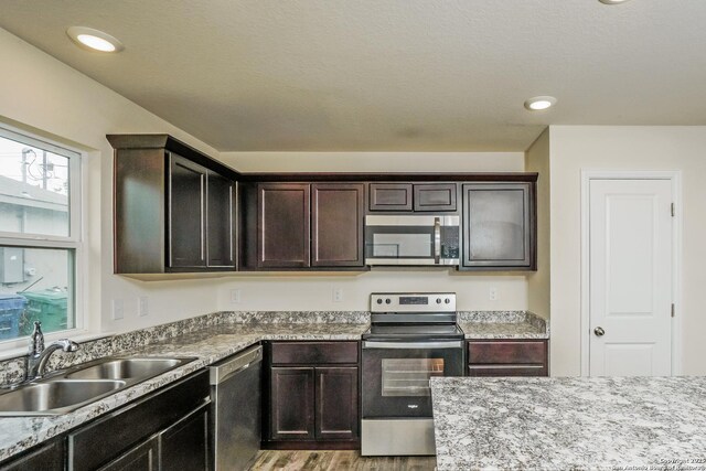 2434 Bermuda, San Antonio, TX 78222 - kitchen with stainless steel appliances, a sink, light wood-style floors, and dark brown cabinets