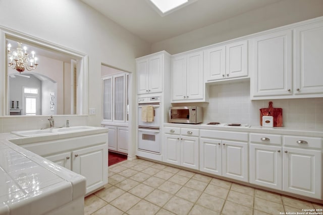 67 Oakwell Farms, San Antonio, TX 78218 - kitchen featuring tile countertops, white appliances, a sink, a chandelier, and white cabinets