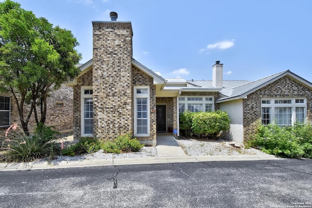 67 Oakwell Farms, San Antonio, TX 78218 - view of front of house with a chimney, a standing seam roof, brick siding, and metal roof